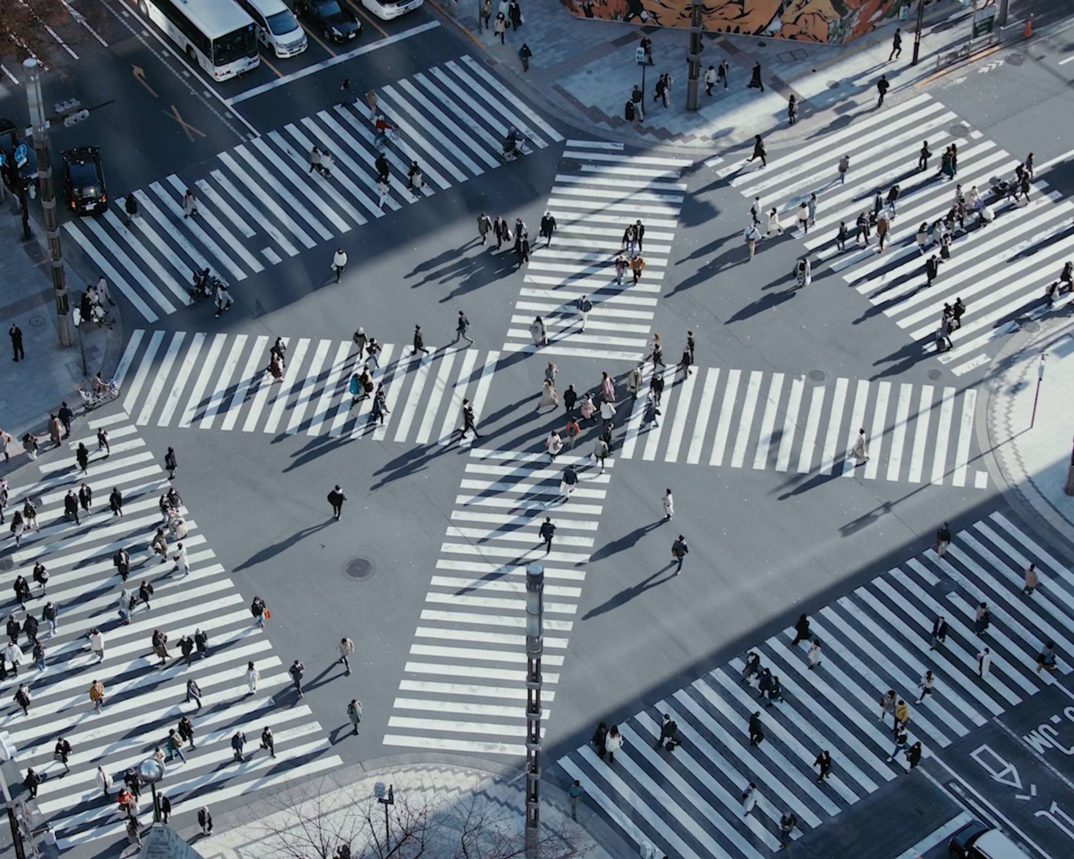 俯瞰風景。数寄屋橋交差点を行き交う冬の装いの人々の長い影が落ちている。々