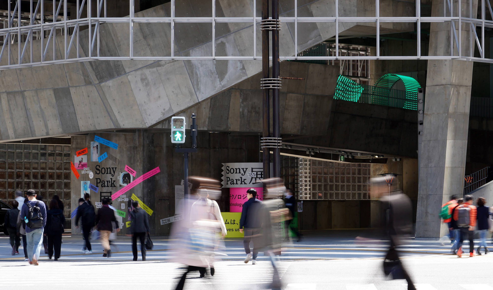 数寄屋橋交差点を渡る人々の背後に見えるGinza Sony Parkの外観。コンクリート建築と緑色のライトが印象的。