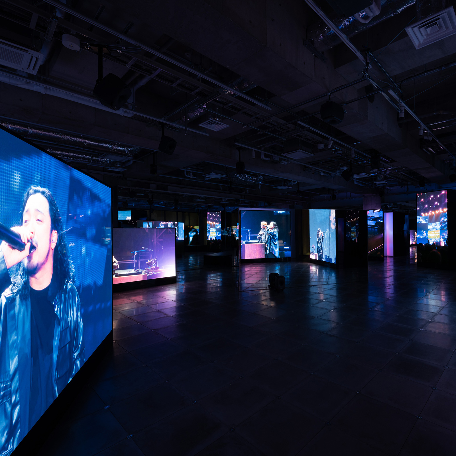 Ginza Sony Park内観。複数の大型スクリーンに映し出されたライブ映像が並ぶ暗い展示空間。