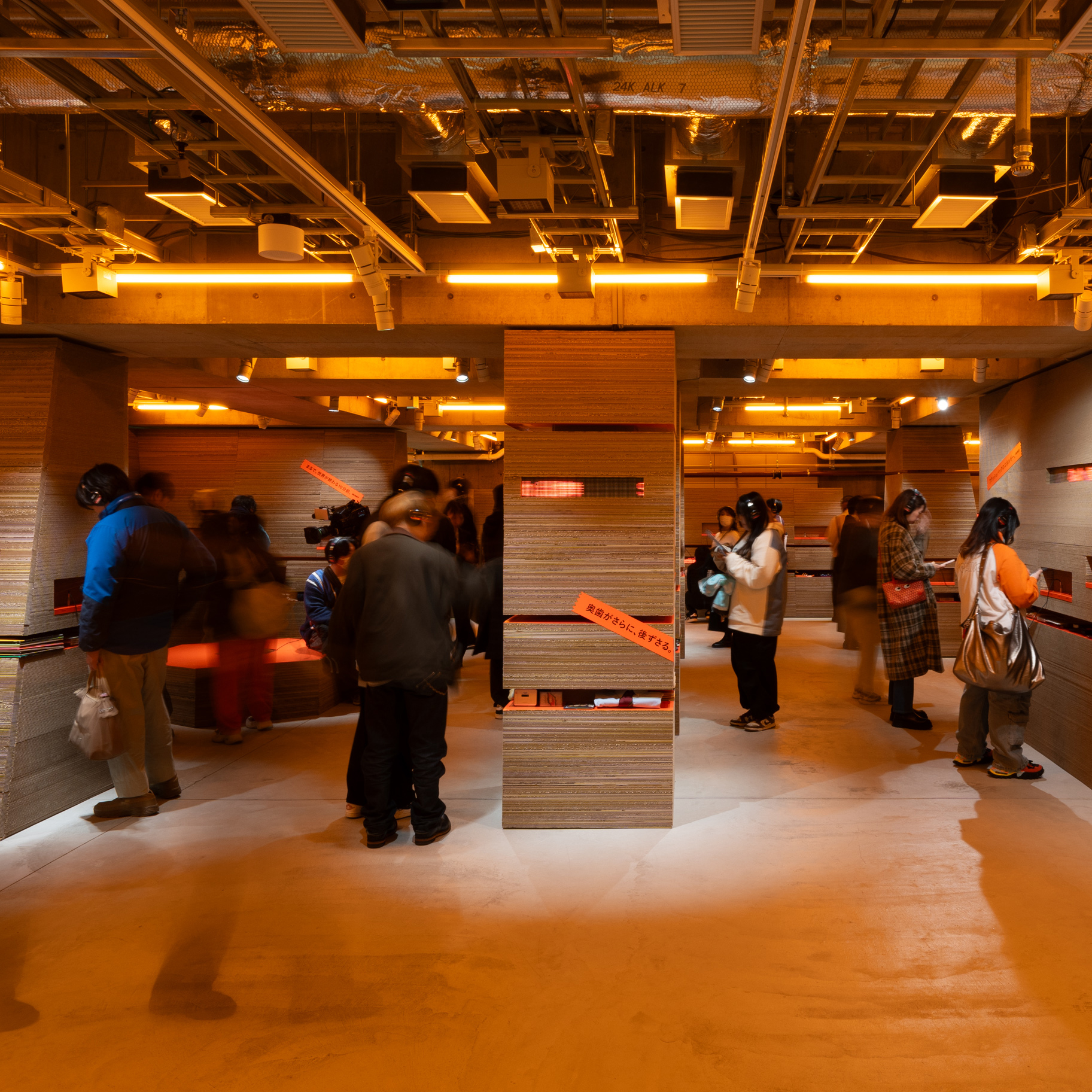 Ginza Sony Park内観。オレンジ色の照明に包まれた展示空間で、来場者がヘッドフォンを付けて体験を楽しんでいる様子。