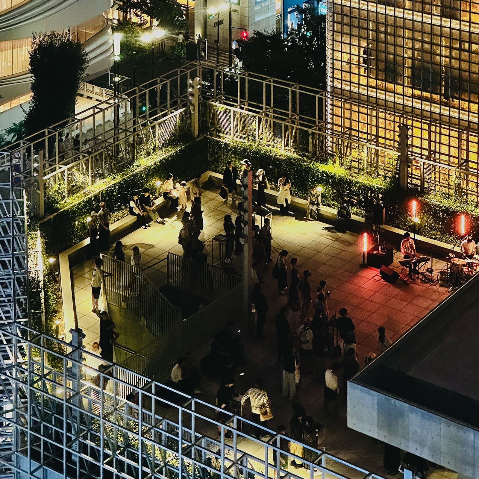 Ginza Sony Park 屋上。夜のライブイベントを楽しむ来園者たち、温かな照明が空間を包んでいる。