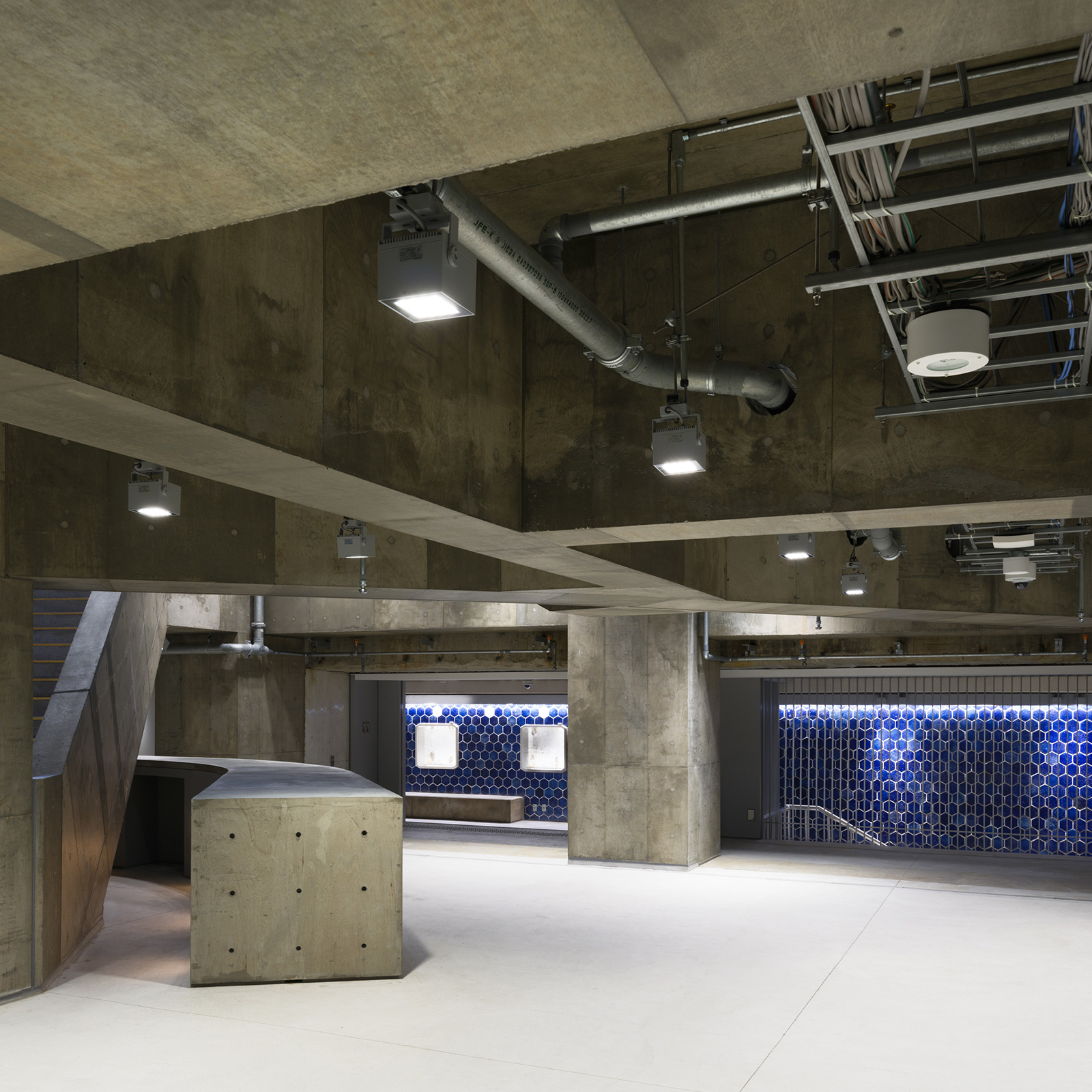 コンクリート造りの広い地下空間。青い六角形タイルの壁が特徴的。