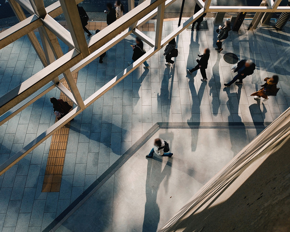 An overhead view inside Ginza Sony Park, showing concrete stairs, long shadows, and people moving through the open public space.