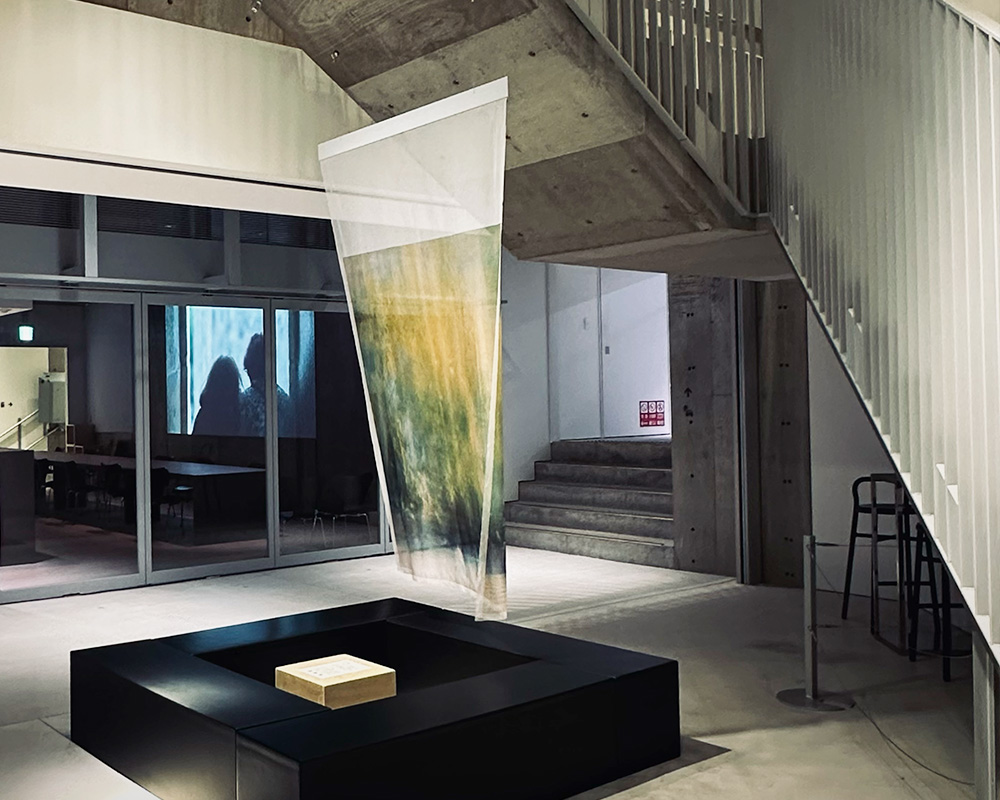 A translucent fabric artwork hangs in the central atrium of Ginza Sony Park, filtering light and adding a soft, layered presence to the architectural space.