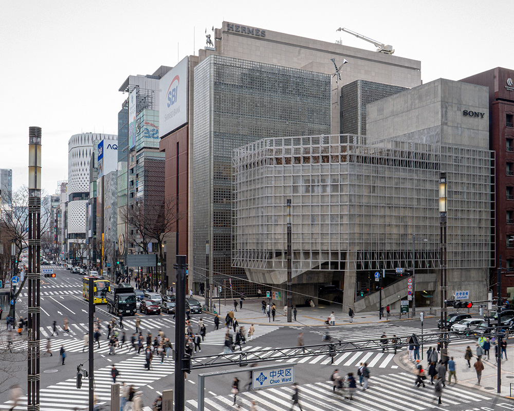 Ginza Sony Park館内の階段空間。打ち放しコンクリートの壁や手すりに囲まれた階段を来園者が降りている様子が映り込んでいる。立体的な動線が建物内をつないでいる。