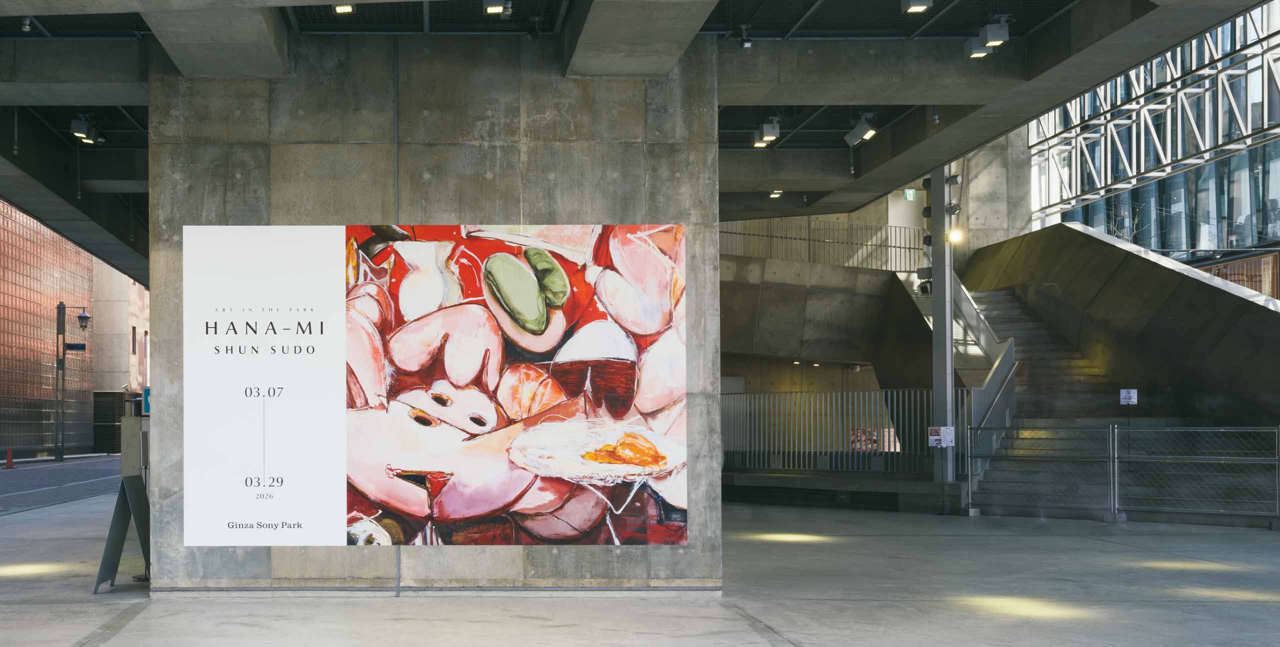Ginza Sony Parkのコンクリート柱に掲示された、「ART IN THE PARK : SHUN SUDO “HANA-MI”」の大型ポスター。吹き抜け階段と都市の通りが奥に広がる。