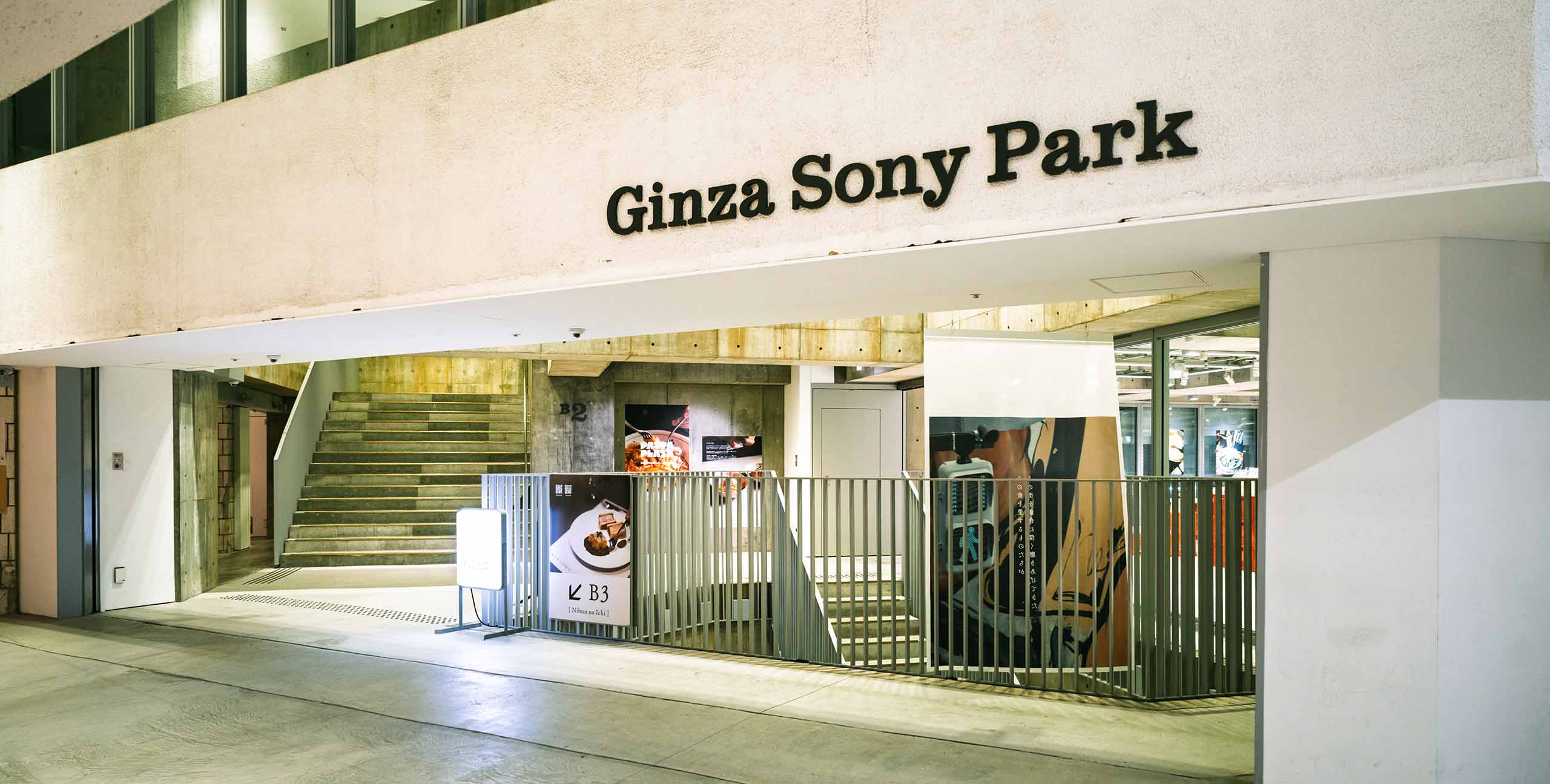 Entrance area on the B2 floor of Ginza Sony Park. Stairs and open circulation lead underground, revealing a spatial connection with the city.